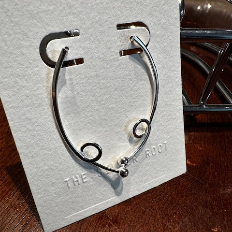 Silver bracelet on a white card with text on a wooden surface