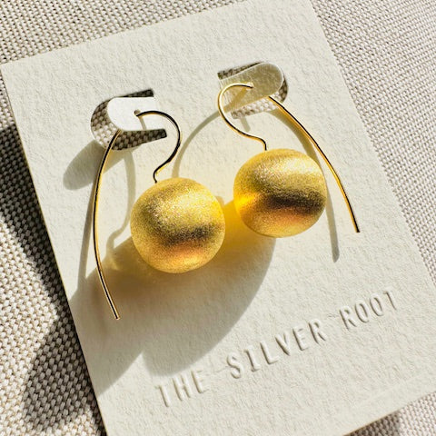 Gold hoop earrings on a card with 'The Silver Root' branding.
